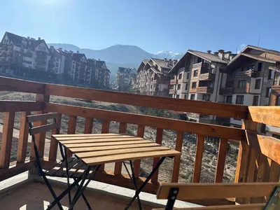 a wooden table and chair on a balcony with buildings at Premium Apartments Bansko in Bansko