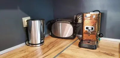 a blender and a microwave sitting on a wooden floor at Къща за гости “Приятели“ in Ovchartsi