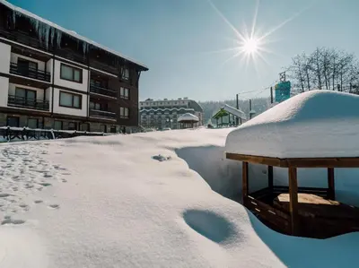 a snow covered building with the sun in the background at Green Life, Bansko, private property in the complex Paradiso Verde, apartman C23 in Bansko