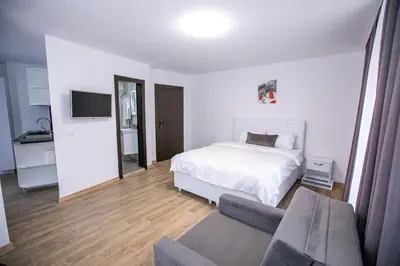 a white bedroom with a bed and a couch at Apartments Monik Sandanski in Sandanski
