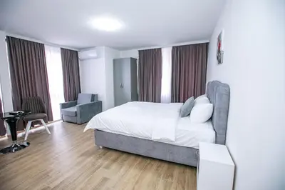 a bedroom with a bed and a desk and chairs at Apartments Monik Sandanski in Sandanski