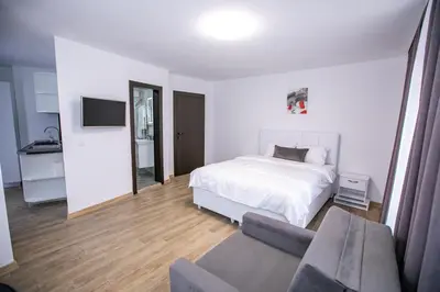 a white bedroom with a bed and a couch at Apartments Monik Sandanski in Sandanski