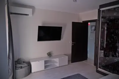 a room with a tv on the wall and a door at Medius Park Apartment in Sandanski