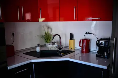 a kitchen counter with a sink and red cabinets at Medius Park Apartment in Sandanski