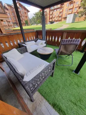 a porch with a bed and a chair on the grass at Vintage studio at Pirin golf in Bansko