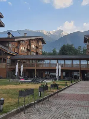 a large building with mountains in the background at Vintage studio at Pirin golf in Bansko