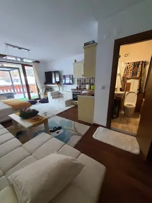 a living room with a white couch and a kitchen at Vintage studio at Pirin golf in Bansko