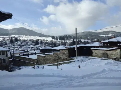 a town covered in snow with buildings and mountains at Тороманова къща in Koprivshtitsa