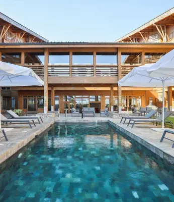 a pool with chairs and umbrellas in front of a building at Pirin Golf Hotel Private Studios in Razlog