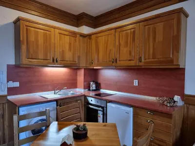 a kitchen with wooden cabinets and a wooden table at Pirin Golf Hotel Private Studios in Razlog