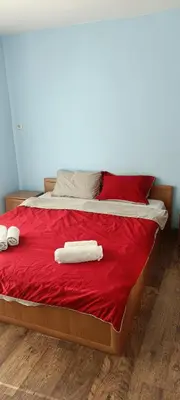 a bed with red sheets and two towels on it at Стаи за гости РИЛА in Rila