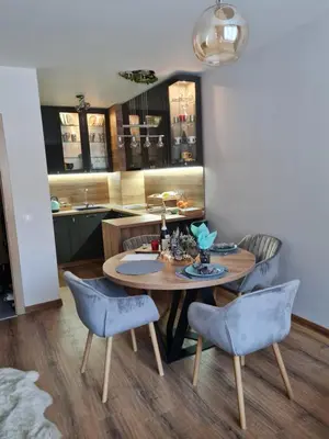 a dining room table with two blue chairs and a kitchen at Mountain Paradise in Aparthotel Borovets Gardens in Borovets