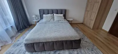 a bedroom with a large bed with a gray headboard at Free SPA Pirin lodge cosy apartment in Bansko