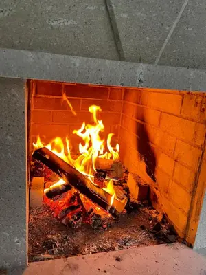 a fire burns inside of a brick oven at Kassandrov Guest House Ravnogor/ Касандрова къща Равногор in Yasă-Koriya