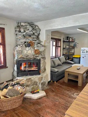 a living room with a stone fireplace at Kassandrov Guest House Ravnogor/ Касандрова къща Равногор in Yasă-Koriya