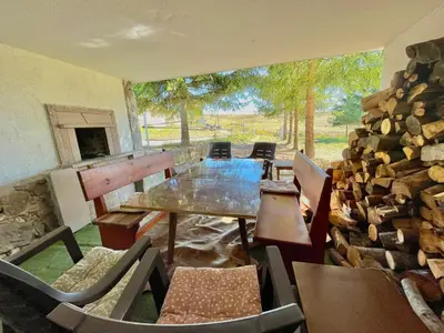 a room with a table and chairs and a stone wall at Kassandrov Guest House Ravnogor/ Касандрова къща Равногор in Yasă-Koriya