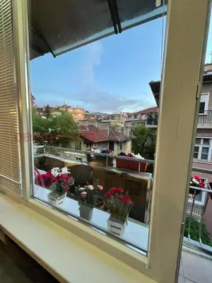 a window with flowers in pots on a ledge at Top center Art deluxe apartment near to Aleksander Nevsky cathedral in Sofia