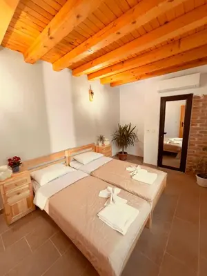 two beds in a large room with wooden ceilings at Къща за гости На Мечка in Oborishte