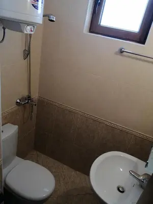 a bathroom with a toilet and a sink and a window at GRAND MONASTERY Apartment ``WHITE TALE`` in Pamporovo