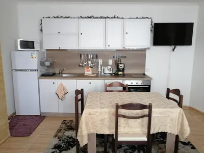 a kitchen with a table with chairs and a refrigerator at GRAND MONASTERY Apartment ``WHITE TALE`` in Pamporovo