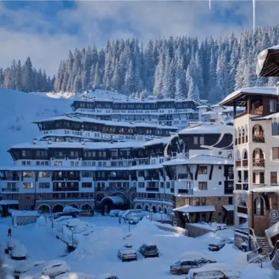 a resort in the snow with cars parked in front at Гранд Манастира Частен Апартамент in Pamporovo