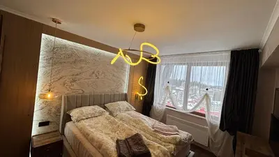 a bedroom with a bed and a chandelier at Гранд Манастира Частен Апартамент in Pamporovo