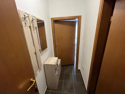 a bathroom with a door and a hallway with a toilet at MH Apartments in Bansko