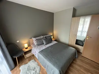 a small bedroom with a bed and a chair at MH Apartments in Bansko