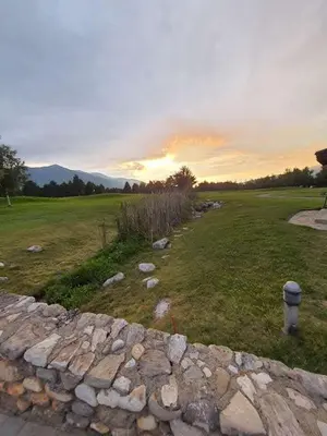 a stone wall in a field with a sunset in the background at Rustic Spa at Pirin Golf in Razlog