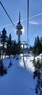 a ski lift with a tower in the snow at BOGI SPA Apartment Pamporovo in Pamporovo
