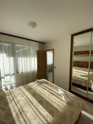 a bedroom with a large bed and a mirror at Borovets Gardens Ski Apartment in Borovets