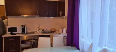 a kitchen with brown cabinets and a purple curtain at Ski Place in Pamporovo