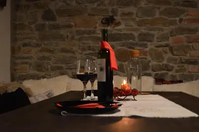 a table with a bottle of wine and two glasses at Yakusha - Якуша, къща за гости in Shiroka Lŭka