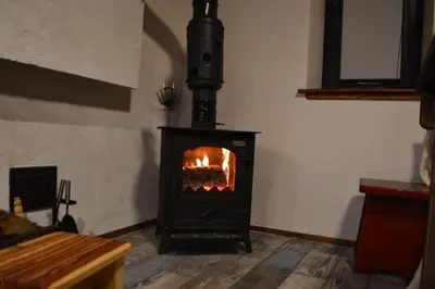 a stove in a room with a fire in it at Yakusha - Якуша, къща за гости in Shiroka Lŭka