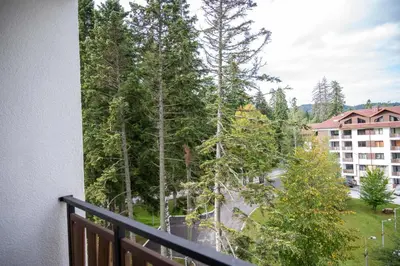 a balcony with a view of trees and a building at All Seasons Apartments Borovets Gardens in Borovets