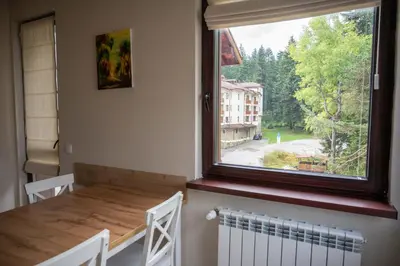 a dining room with a table and a large window at All Seasons Apartments Borovets Gardens in Borovets