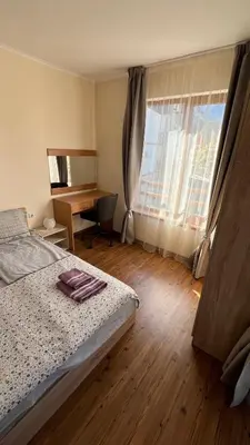 a bedroom with a bed and a desk and a window at Vesta Boutique Apartment in Bansko