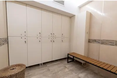a dressing room with white cabinets and a bench at Баня Аква Ризорт in Banya