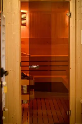 a glass shower in a bathroom with a tub at Family hotel Andreev in Dobrinishte
