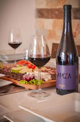 a bottle of red wine next to a plate of food at Family hotel Andreev in Dobrinishte