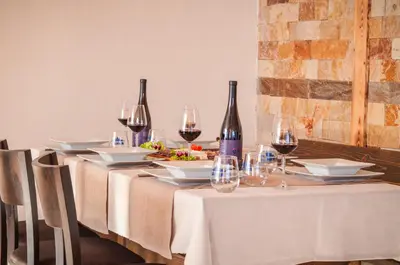 a table with wine glasses and plates of food at Family hotel Andreev in Dobrinishte