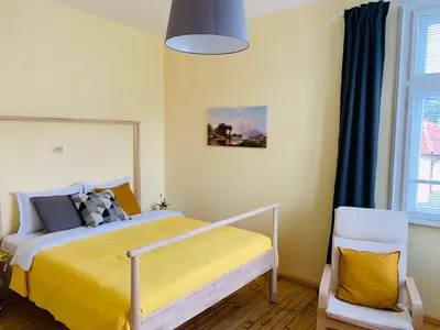 a bedroom with a bed with a yellow blanket at TÁNIN HOUSE - Three-bedroom apartment, sauna and gym 10' away from Borovets in Samokov