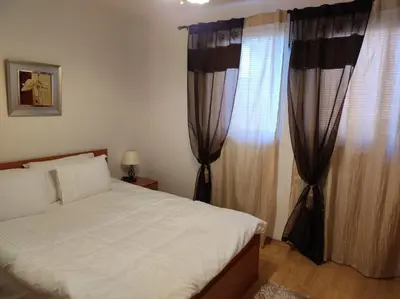 a bedroom with a bed and a window with curtains at Neviasta Apartment in Smolyan