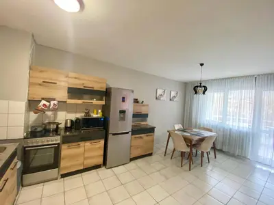 a kitchen with a table and a stainless steel refrigerator at Spacious Apartment next to South Park Просторен Апартамент до Южен Парк Top Location in Sofia