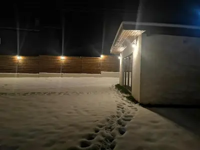 a building covered in snow at night with lights at Algarte Guest House in Madzhare