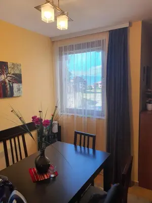 a dining room table with a vase on it with a window at Koko's apartments 2 in Bansko