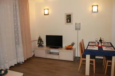 a living room with a table and a television on a cabinet at Apartment Kristin in Apart Hotel Stenata in Pamporovo