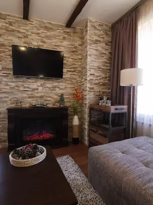 a living room with a fireplace and a tv on a brick wall at Cedar 42 in Bansko