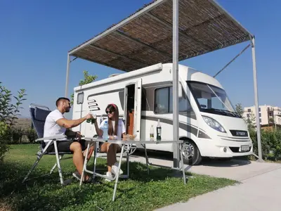 a man and woman sitting at a table in front of an rv at Camping Alliance in Plovdiv