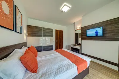 a bedroom with a bed with orange pillows and a tv at 4 Seasons Apartment 535, Oak Residence in Smolyan